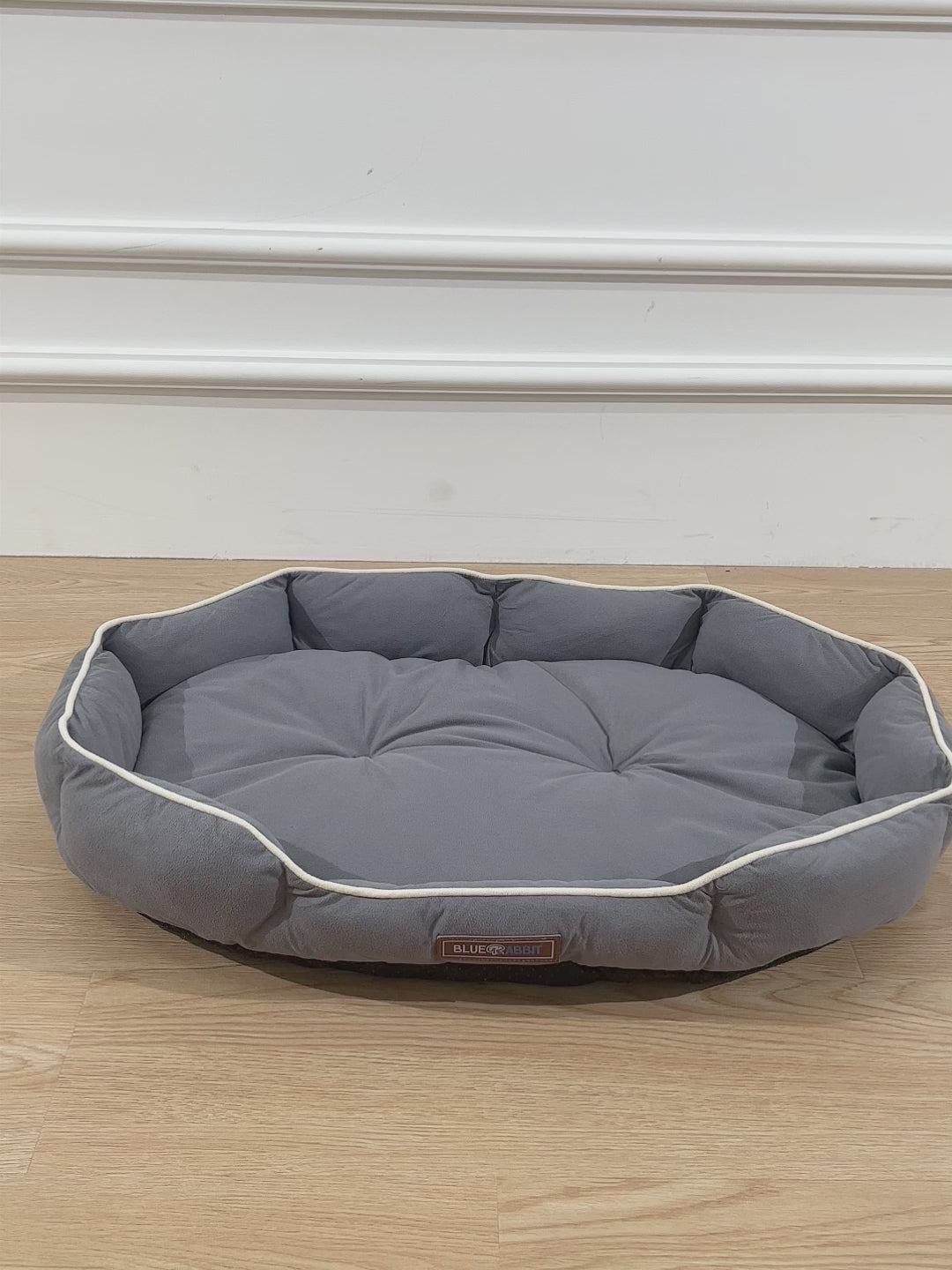 Hexagonal gray pet bed on a wooden floor