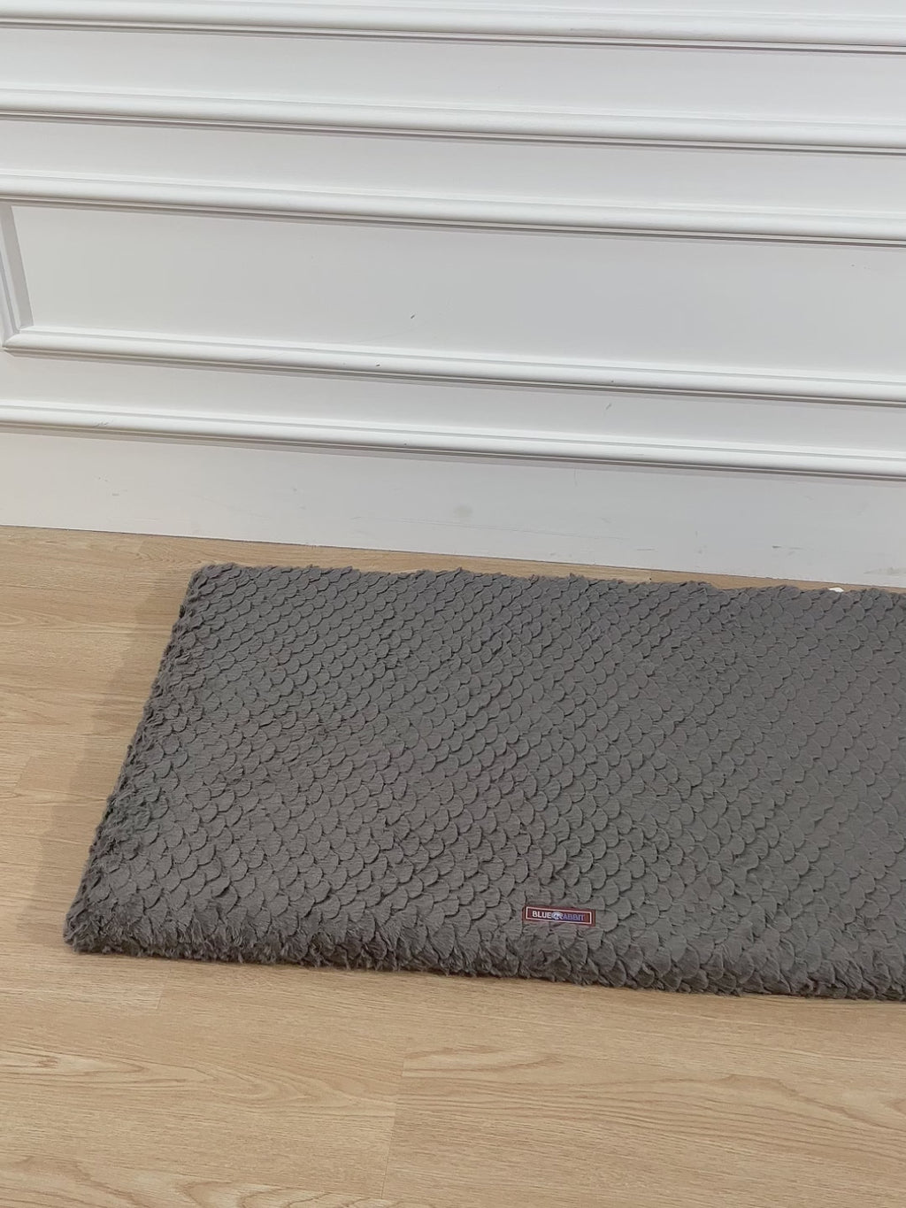 Gray textured rug on a wooden floor with a blurred background