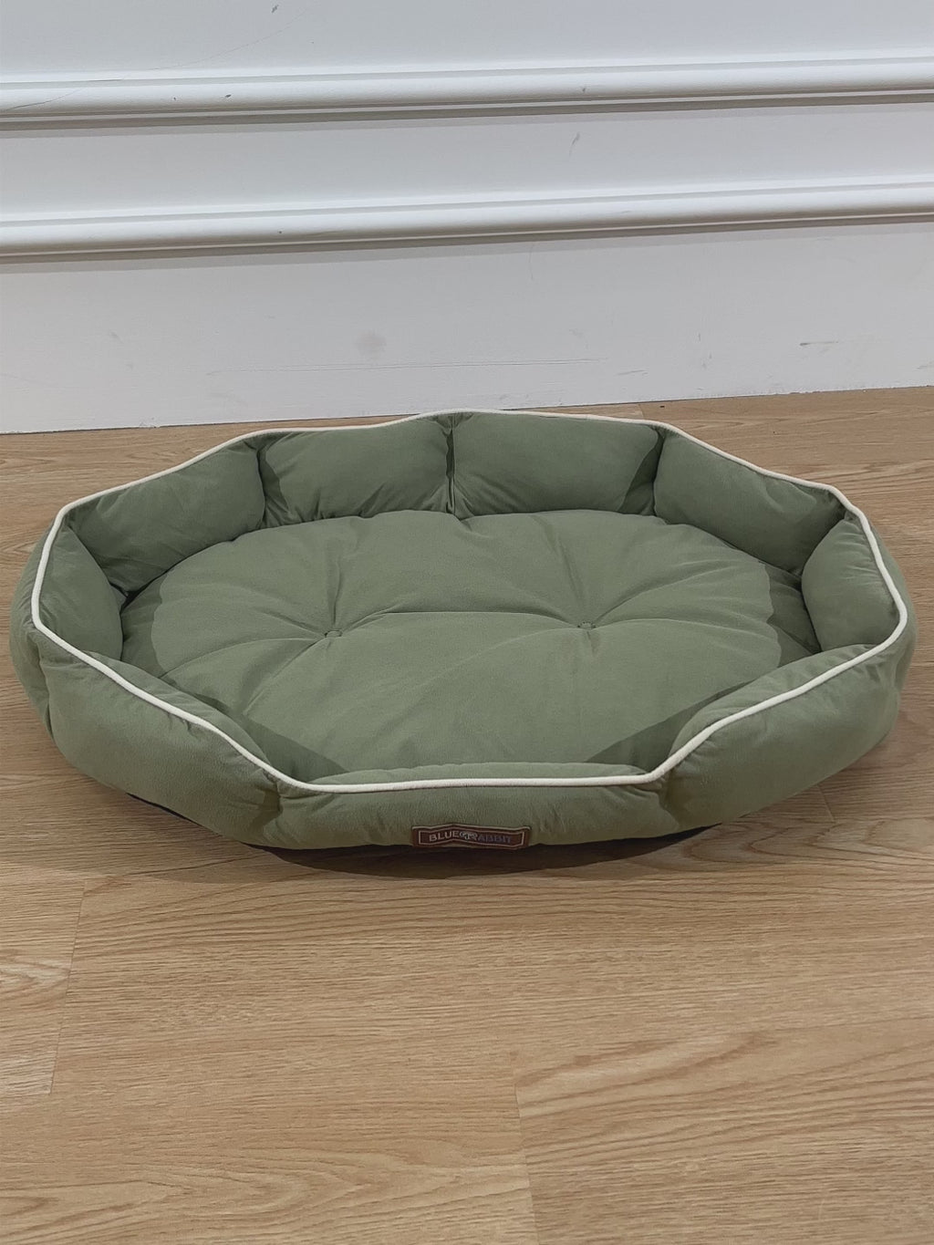 Green octagonal pet bed on a wooden floor 