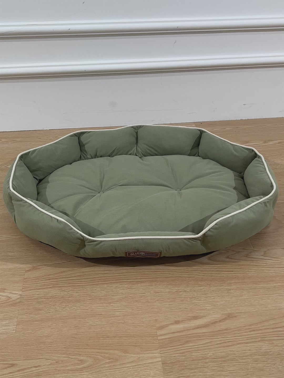 Green octagonal pet bed on a wooden floor 